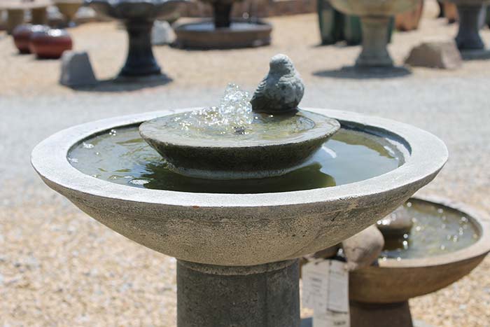 Bird bath with fountain and small stone bird statue