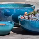 Three blue pottery planters, one holding succlents