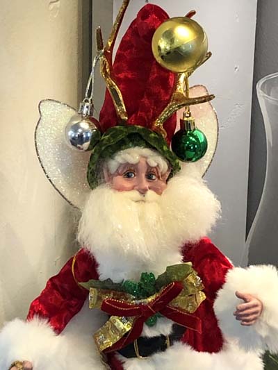 A Mark Roberts fairy, dressed like Santa with ornaments on hat and wearing a red coat