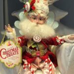 A Mark Roberts Christmas fairy wearing various candy and holding a sign that says "Christmas Treats"