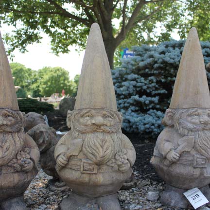 Three gnome statues for sale in Cincinnati, OH sitting in front of a large bush