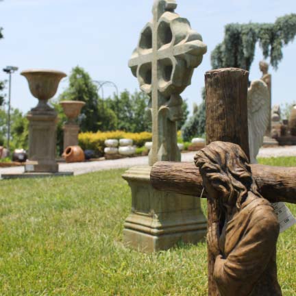 Cast stone statue of Jesus with cross with Celtic cross and other statues for sale in background