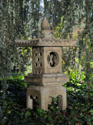 Garden statue of footed Japanese lantern under willow tree